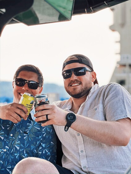 Two people sitting in a vehicle, holding drinks. 4