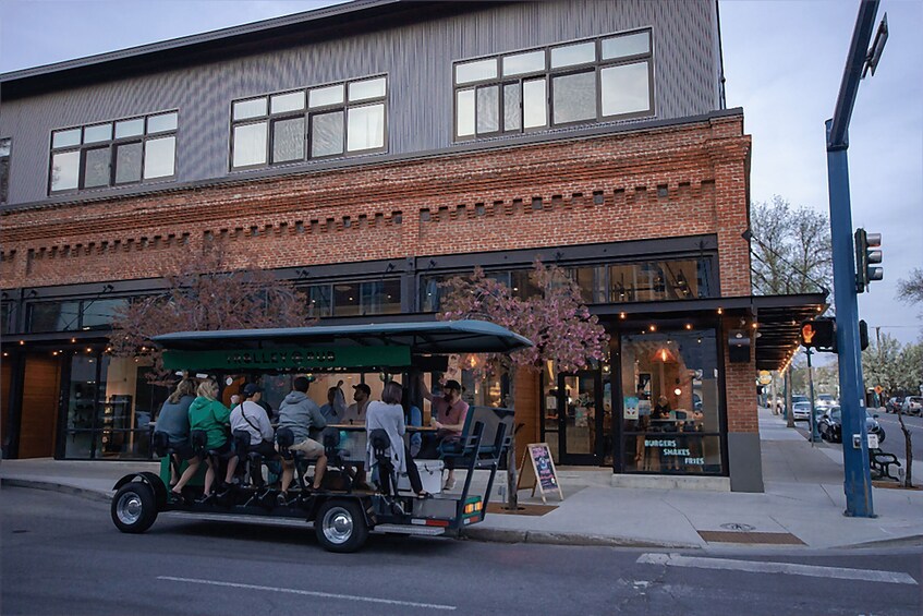 A street with a brick building, a green-roofed cart with people, and a restaurant with a sign. 5