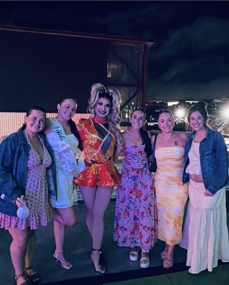 A group of people posing for a photo at an outdoor event with a building in the background. 3