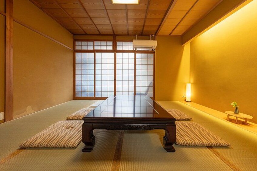 A tatami mat room with a low table, sliding doors, and a small table with a vase. 3