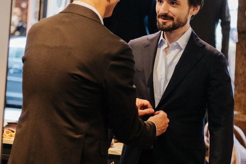 Two men in suits, one adjusting the other's tie. 4
