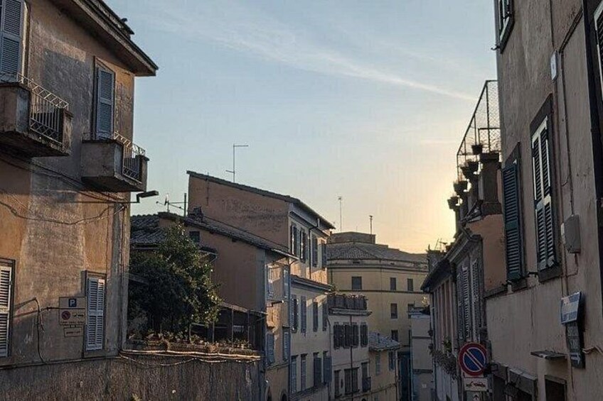 A narrow street with buildings, a no parking sign, and a clear sky. 5