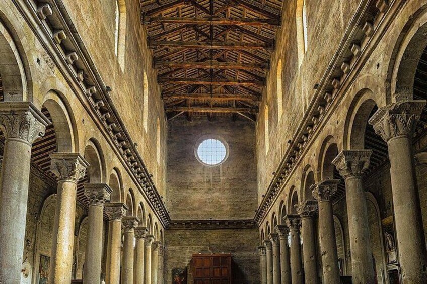 An interior of a historical building with columns, arches, and a wooden ceiling. 2