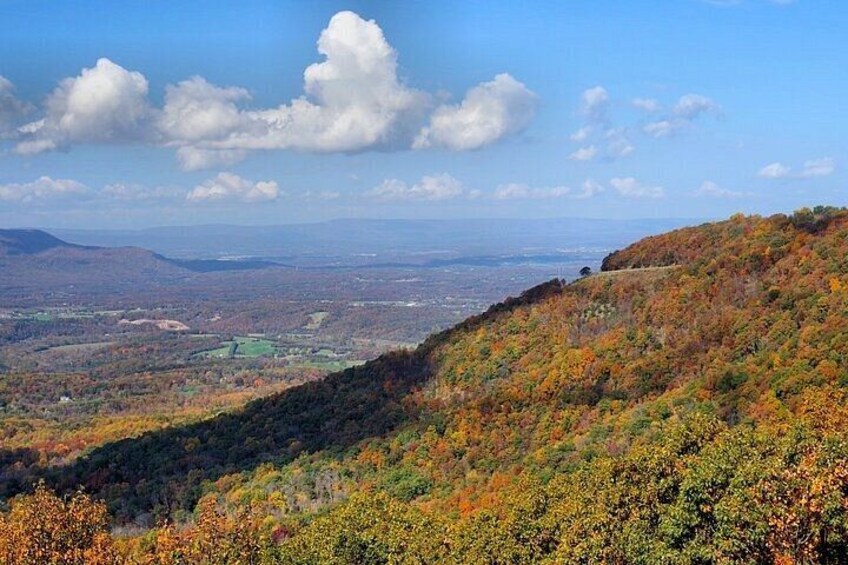 A hilly landscape with autumn foliage, a distant valley, and a clear sky. 3