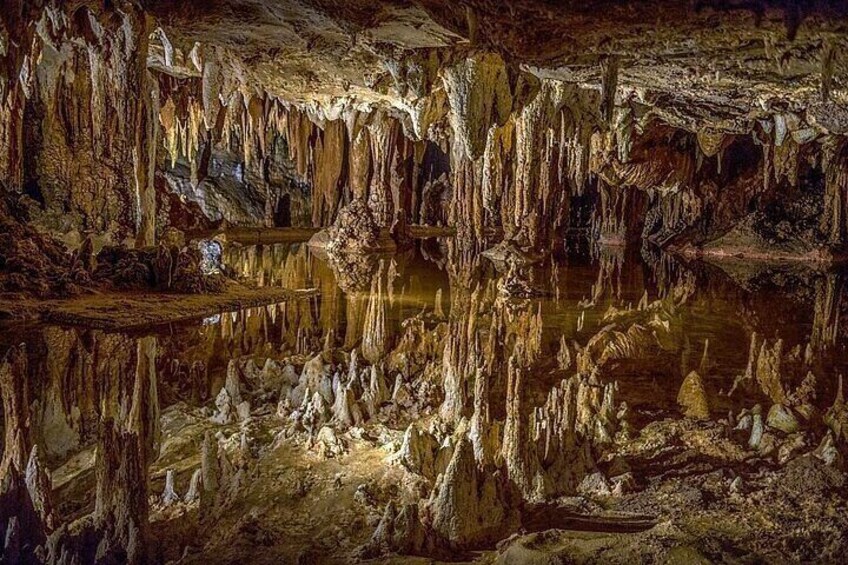 Une grotte ornée de stalactites et de stalagmites, un bassin d’eau et une plateforme en bois. 4