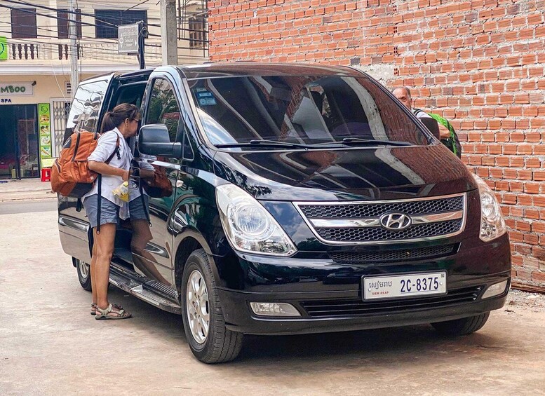 A black van parked by a brick wall with a person standing beside it. 2