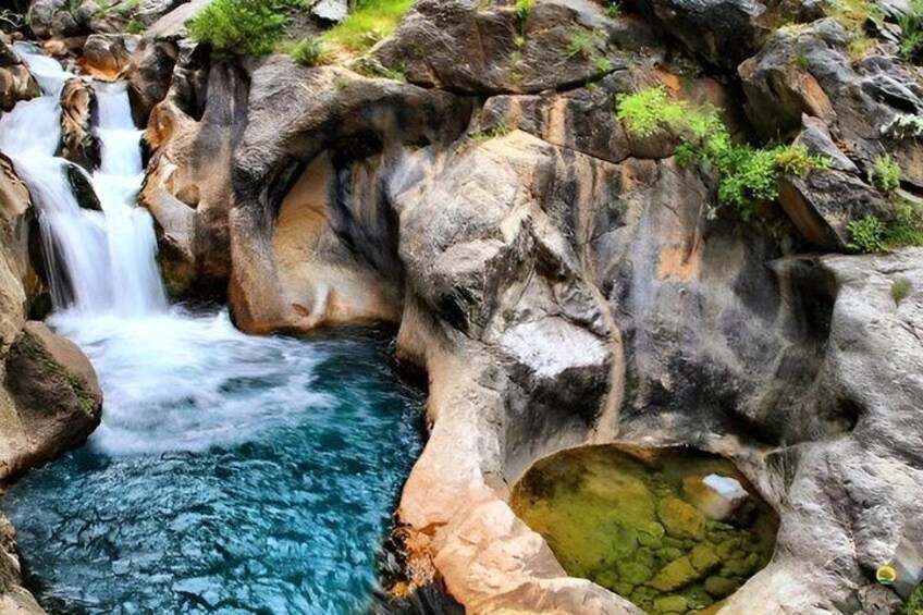 A waterfall cascading into a clear pool surrounded by rocky terrain. 3