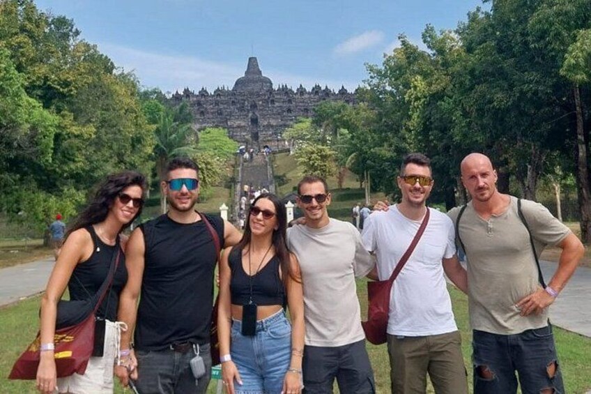 A group of people posing in front of a historical structure with a staircase leading up to it. 2