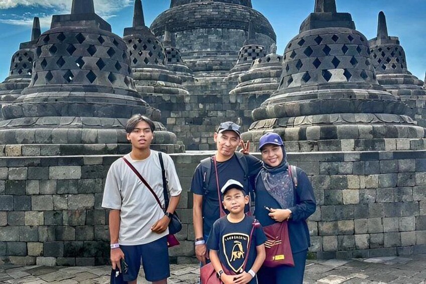 A group of people standing in front of ancient stone structures with multiple tiers and intricate designs. 1