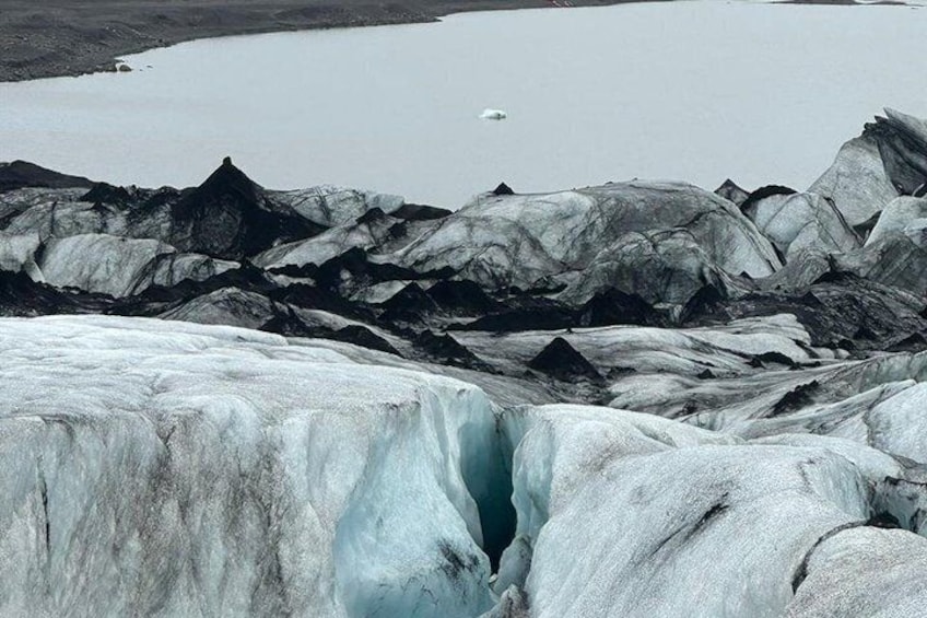 A glacier with a crevasse, icebergs, and a body of water. 4