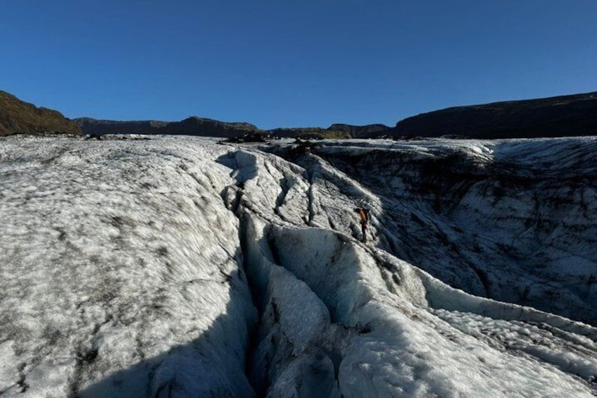 A glacier with a crevasse and a person standing at the edge. 2