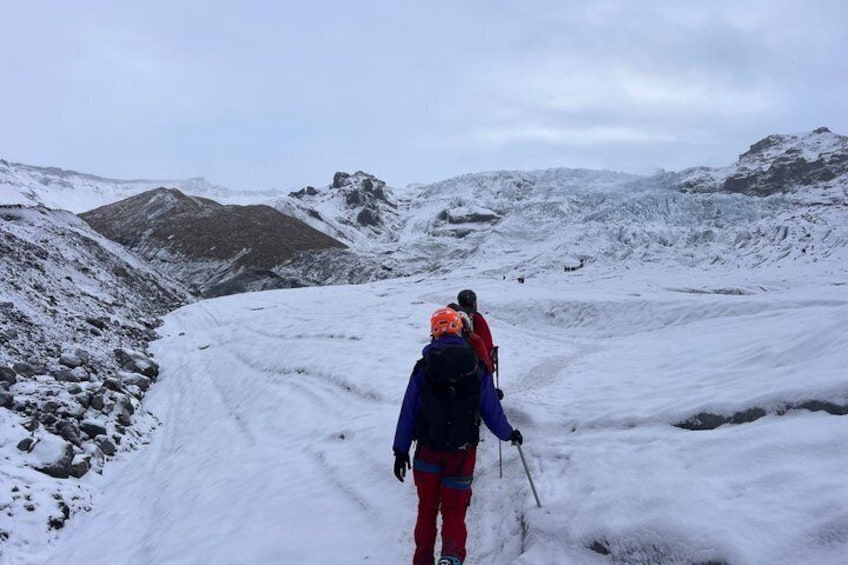 A snowy mountain landscape with a person in red and blue gear walking away from the camera. 3