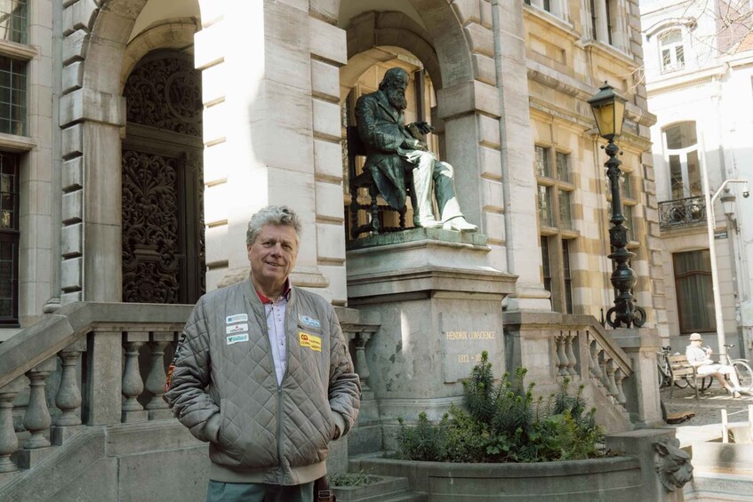 A man standing in front of a building with a statue and a plaque reading 'Hendrik Conscience 1812-1898'. 2