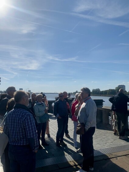 A group of people standing on a waterfront promenade, overlooking a body of water with a clear sky above. 4