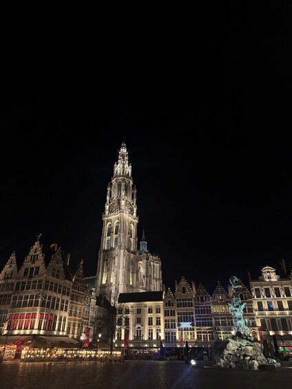 A historic cathedral with intricate architecture, illuminated by night lights, and a statue in the foreground. 1