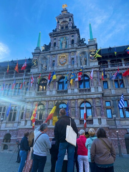 A historic building with ornate architecture, multiple flags, and a prominent crest. 5