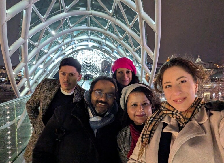 A group of people on a glass bridge with a metal framework and lights. 4
