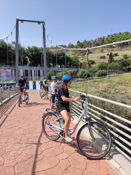 A group of cyclists on a bridge with a scenic view of hills and trees. 2