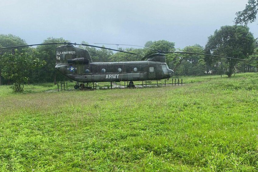 En militärhelikopter med texten ”ARMY” målad på sidan, parkerad på en gräsplätt med träd i bakgrunden. 3