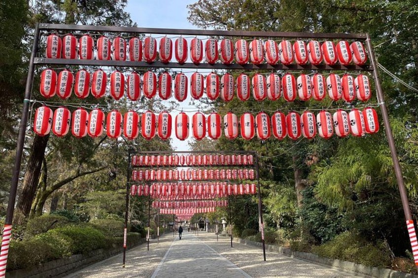 A pathway with a large sign featuring red and white lanterns. 3