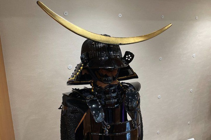 A person in a samurai costume with a large curved horn on their head. 5