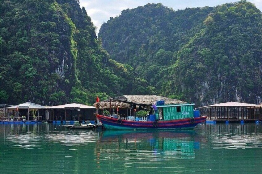 A colorful boat docked at a floating structure with lush green hills in the background. 5