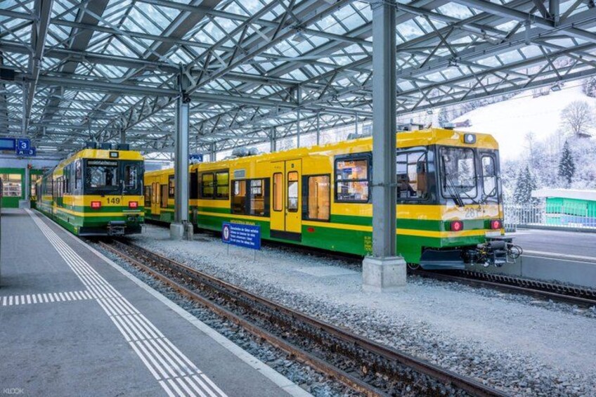 A train station with two trains, snow on the ground, and a covered platform. 3