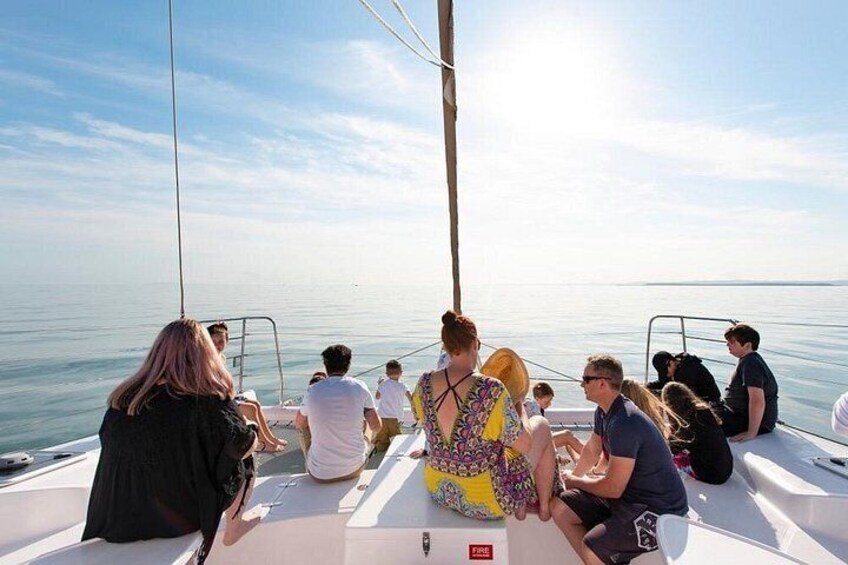 A group of people on a sailboat with a calm sea and clear sky in the background. 5