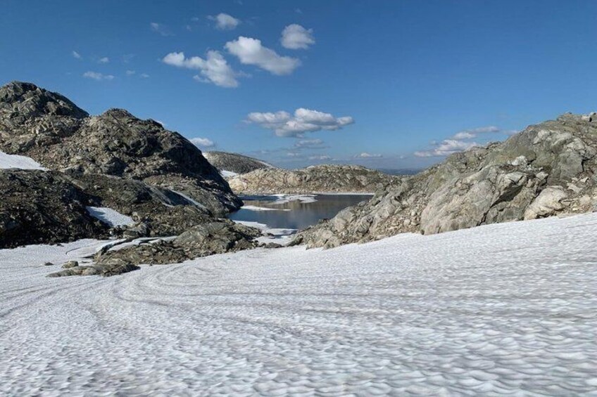 A snowy mountain landscape with a lake and rocky terrain. 2
