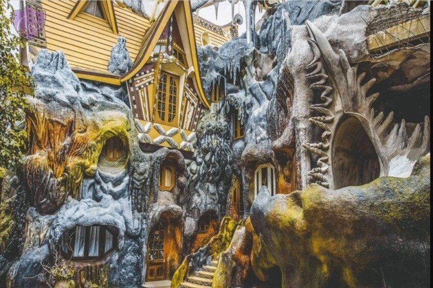 A fantastical architectural structure with a wooden house, a staircase, and a large cave-like entrance. 2