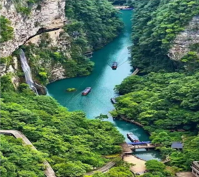 A river with boats, surrounded by dense greenery and cliffs. 5