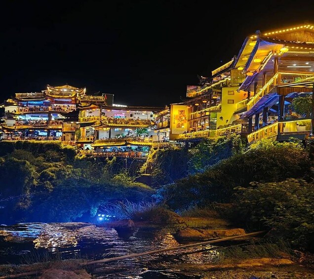 A brightly lit traditional building complex at night with a river in the foreground. 4