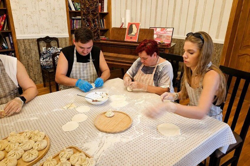 A group of people preparing food at a table with dough and utensils. 3