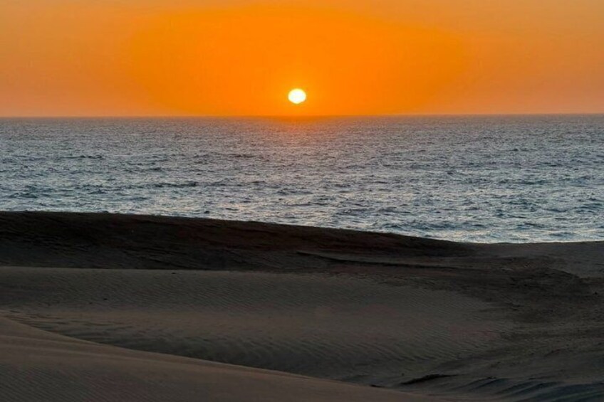 Ein Sonnenuntergang über einem Strand mit Dünen und dem Meer. 4