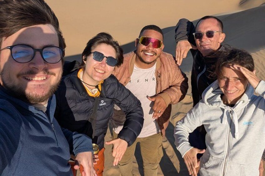 Un grupo de personas al aire libre, algunas con chaquetas y una sosteniendo una cámara. 5