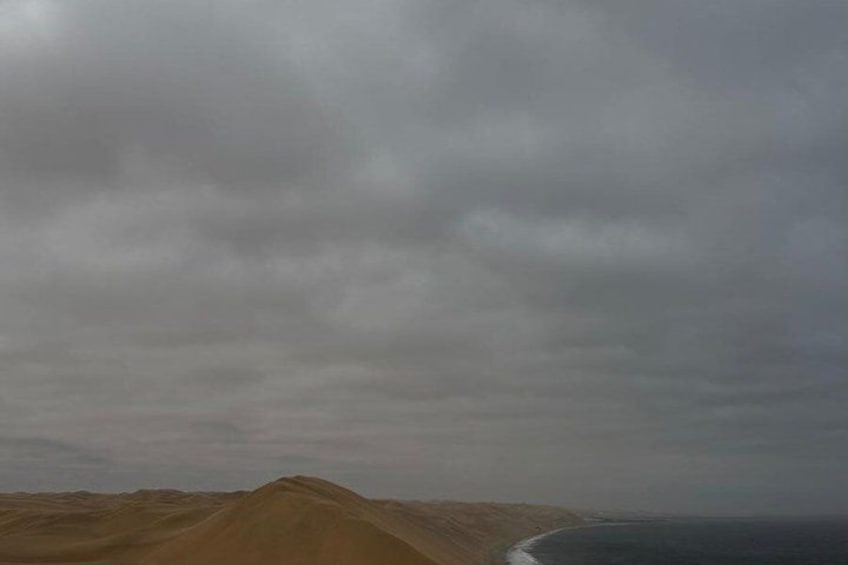 Paisaje desértico con dunas de arena y una masa de agua. 2