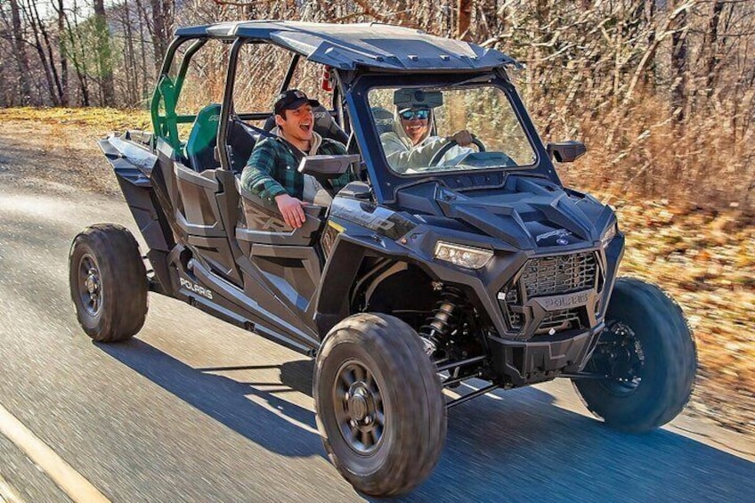 A Polaris ATV driving on a paved road with trees in the background. 5