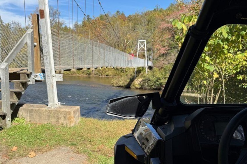 A car's dashboard and a suspension bridge over a river. 1