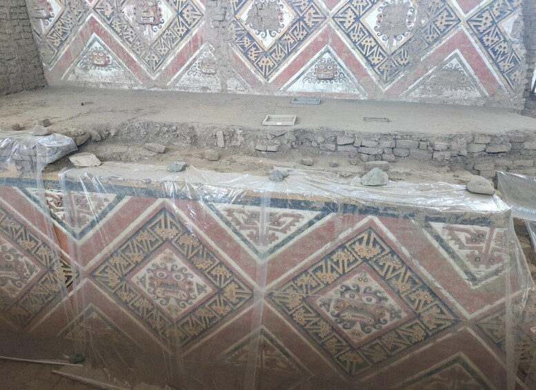 An archaeological site with patterned wall tiles and exposed brickwork. 3