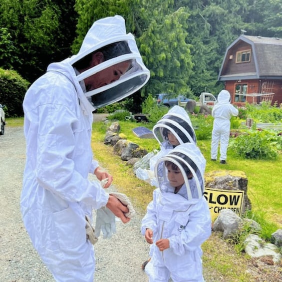 People in protective suits and helmets, possibly for a scientific or environmental activity, in a rural setting with a gravel path and greenery. 4