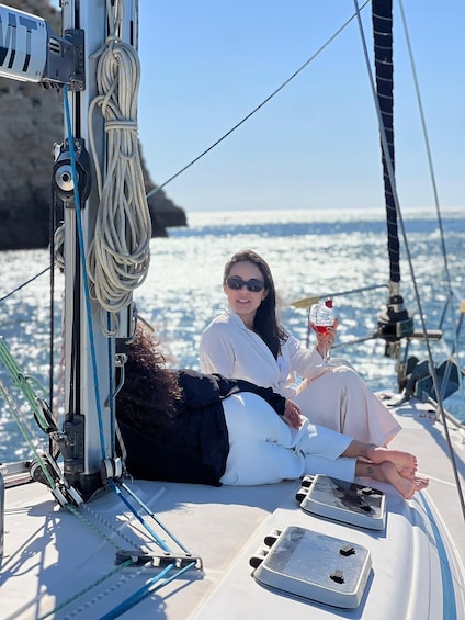 A person on a sailboat with ropes and a winch, a clear sky, and the ocean in the background. 5