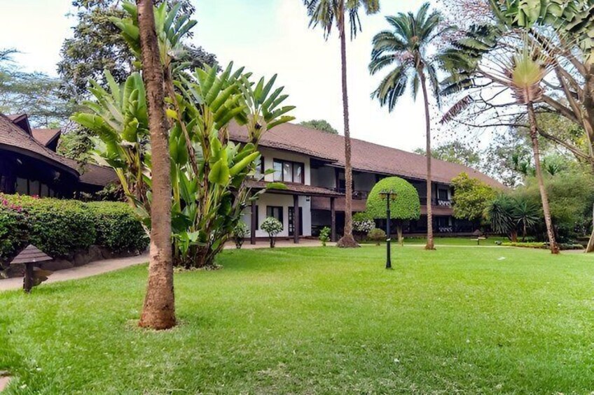 A building with a curved roof, surrounded by lush greenery and palm trees. 4