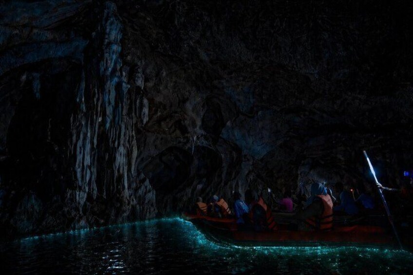 A boat tour through a cave with illuminated water. 2