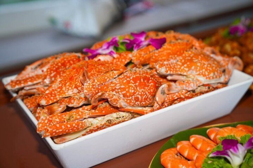 A white rectangular dish filled with cooked crabs, garnished with purple flowers. 4