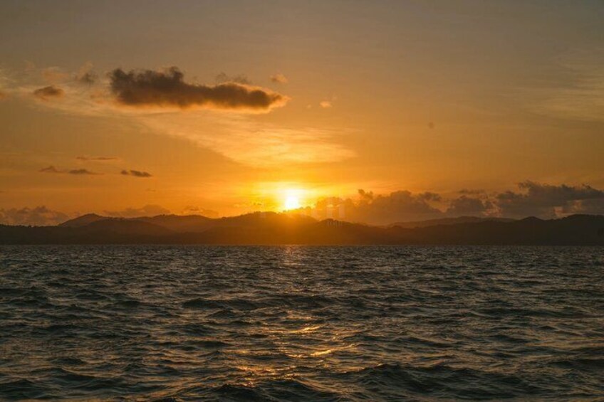 A sunset over a body of water with mountains in the background. 3