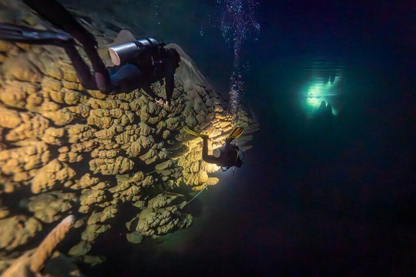 A diver exploring underwater cave formations with a flashlight. 2