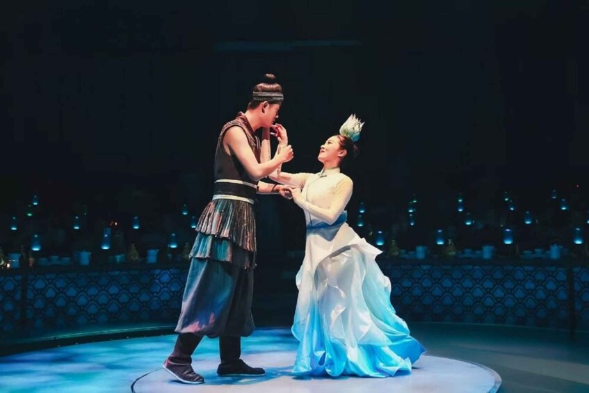 A stage with two performers in traditional costumes, a patterned backdrop, and a circular stage. 3