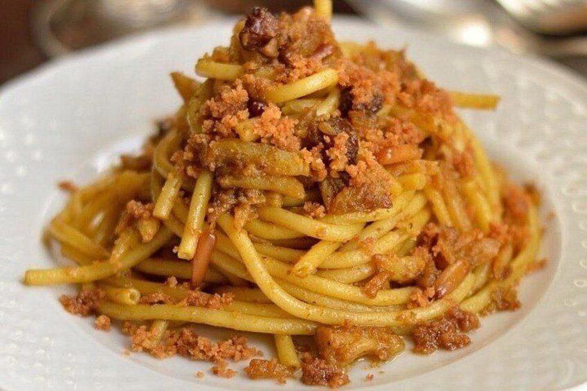 En tallrik med spaghetti, köttfärssås och ströbröd. 3