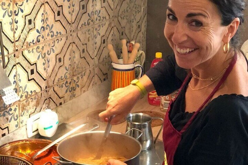 Une personne cuisine sur une cuisinière, utilisant une grande marmite, une cuillère en bois et une casserole en métal posée sur le plan de travail. 2