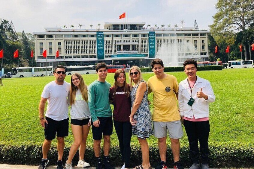 Un groupe de personnes posant devant un grand bâtiment orné d’une fontaine et décoré de drapeaux rouges. 5